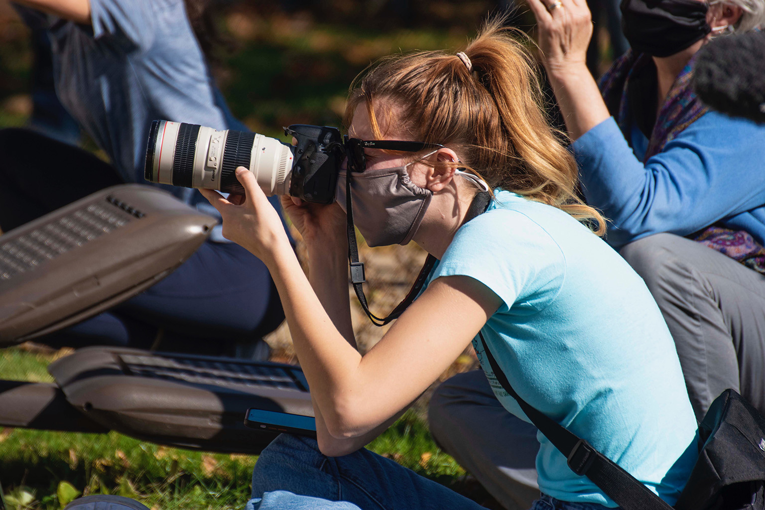 A journalism student takes a picture with a professional photo camera.